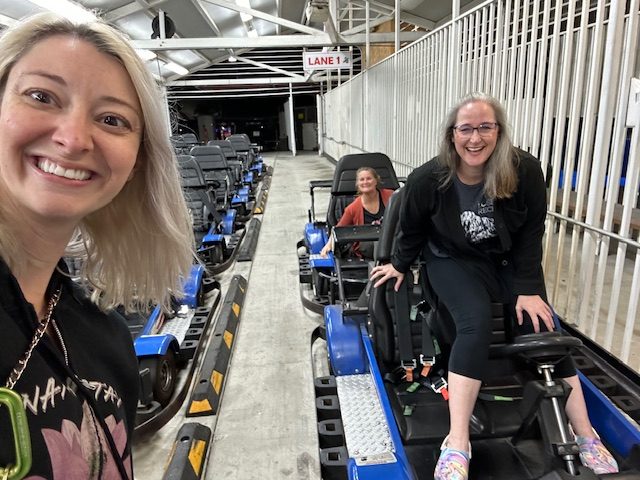 Jennifer Swann and two friends laughing as they enter bumper cars at an amusement park.
