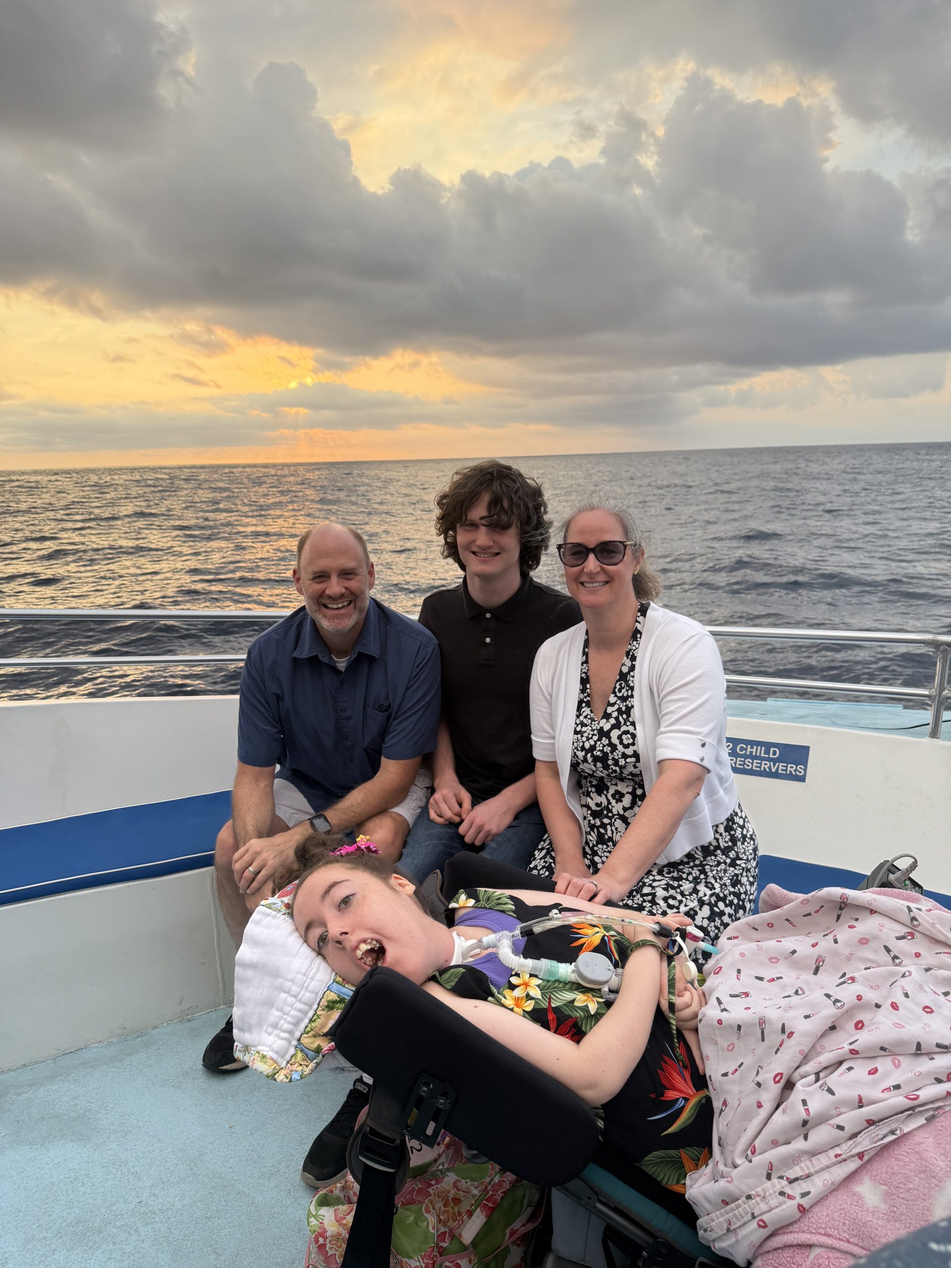 The full Swann family sitting on a boat at sunset, with clouds and the ocean in the background.