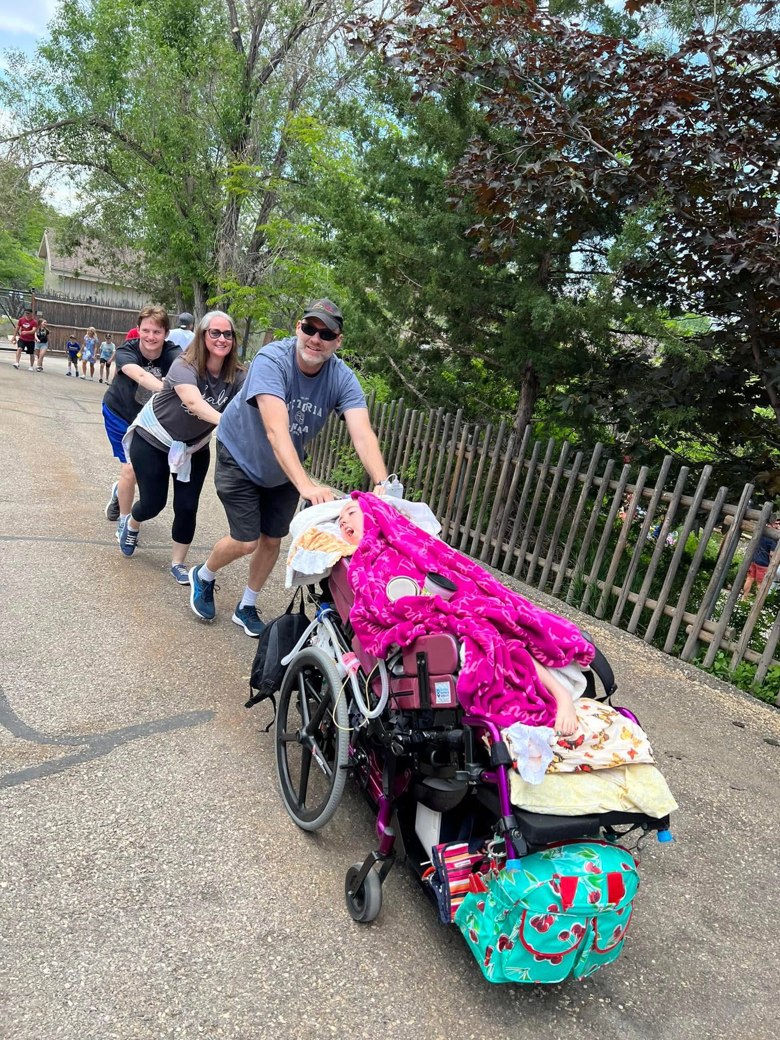 Kennedy is pushed through the park on a sunny day by her whole family.