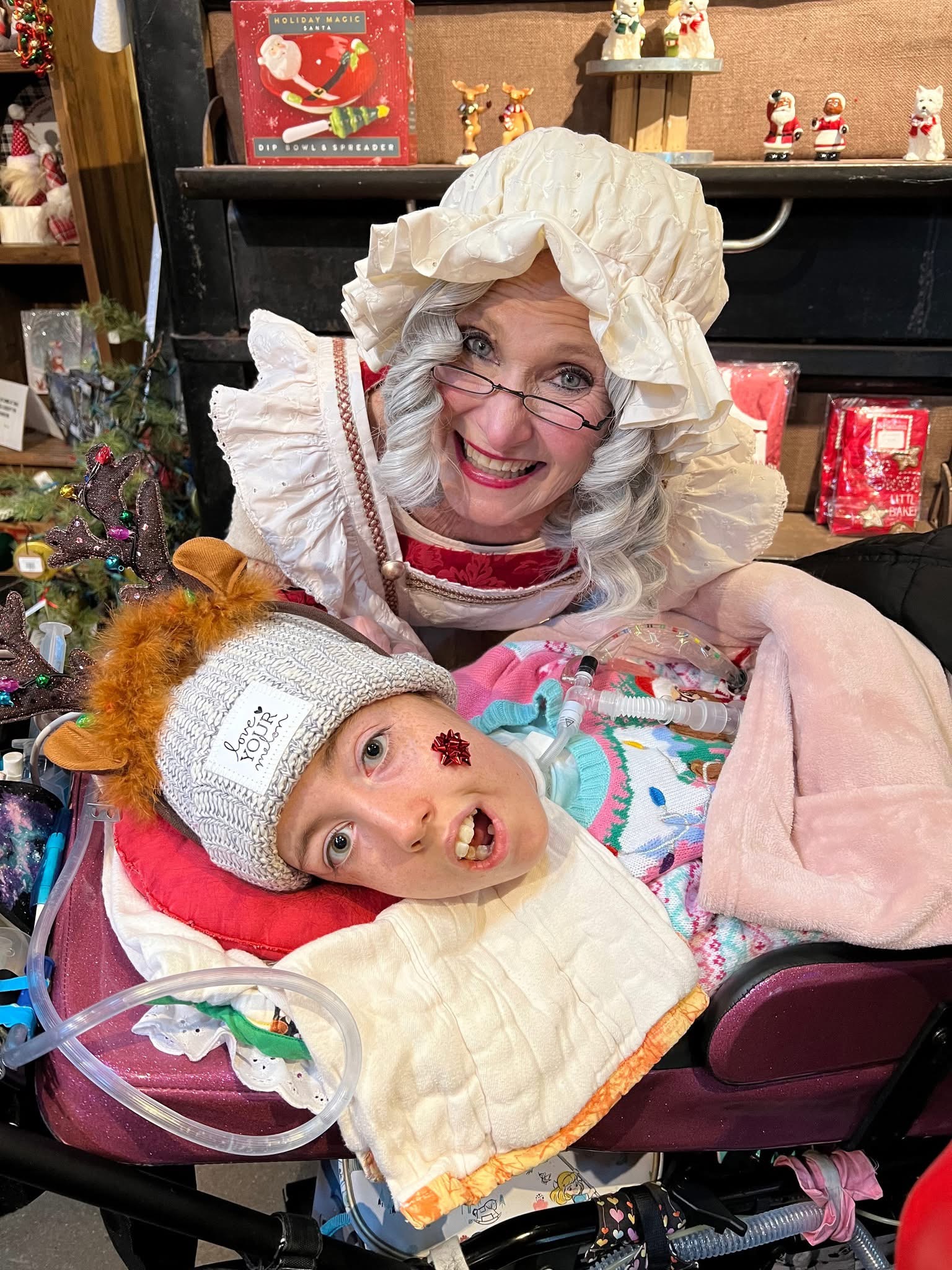 Smiling Mrs. Claus and Kennedy surrounded by Christmas decorations.