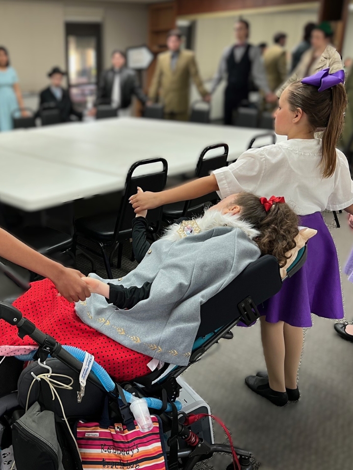 Kennedy holds hands with the cast of a musical.