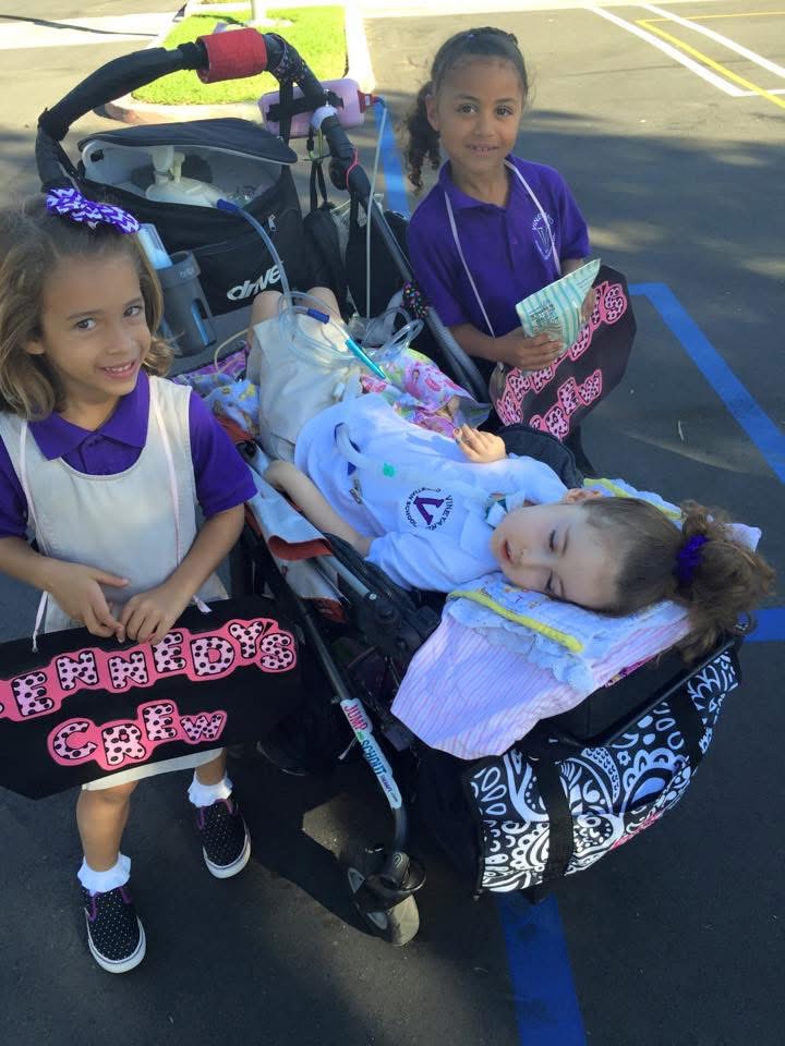 Kennedy and her friends in kindergarten pose together. Her friends have bags that read "Kennedy's Crew."